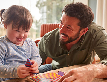 Dad and daughter playing with blocks at a table