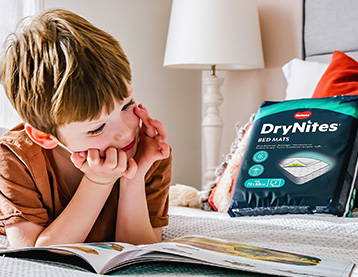 A boy lying on his bed and reading a book