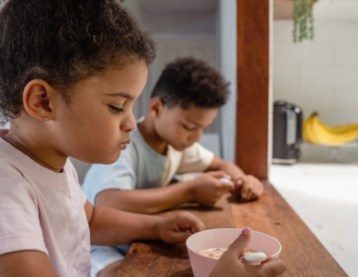 Boy and girl eating cereal at a kitchen counter