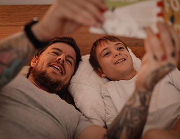 Dad and son lying on their backs looking at a book