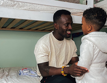 Dad sitting on a bunk bed talking to his son