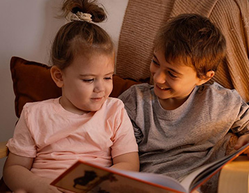 Smiling siblings looking through a storybook