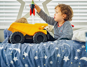 Young boy sitting in his bed playing with a toy truck