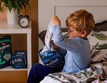 Boy taking DryNites Pyjama Pants from the packaging