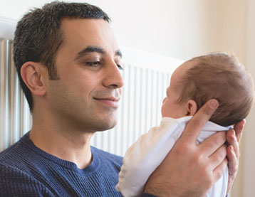 Father looking lovingly at newborn baby.